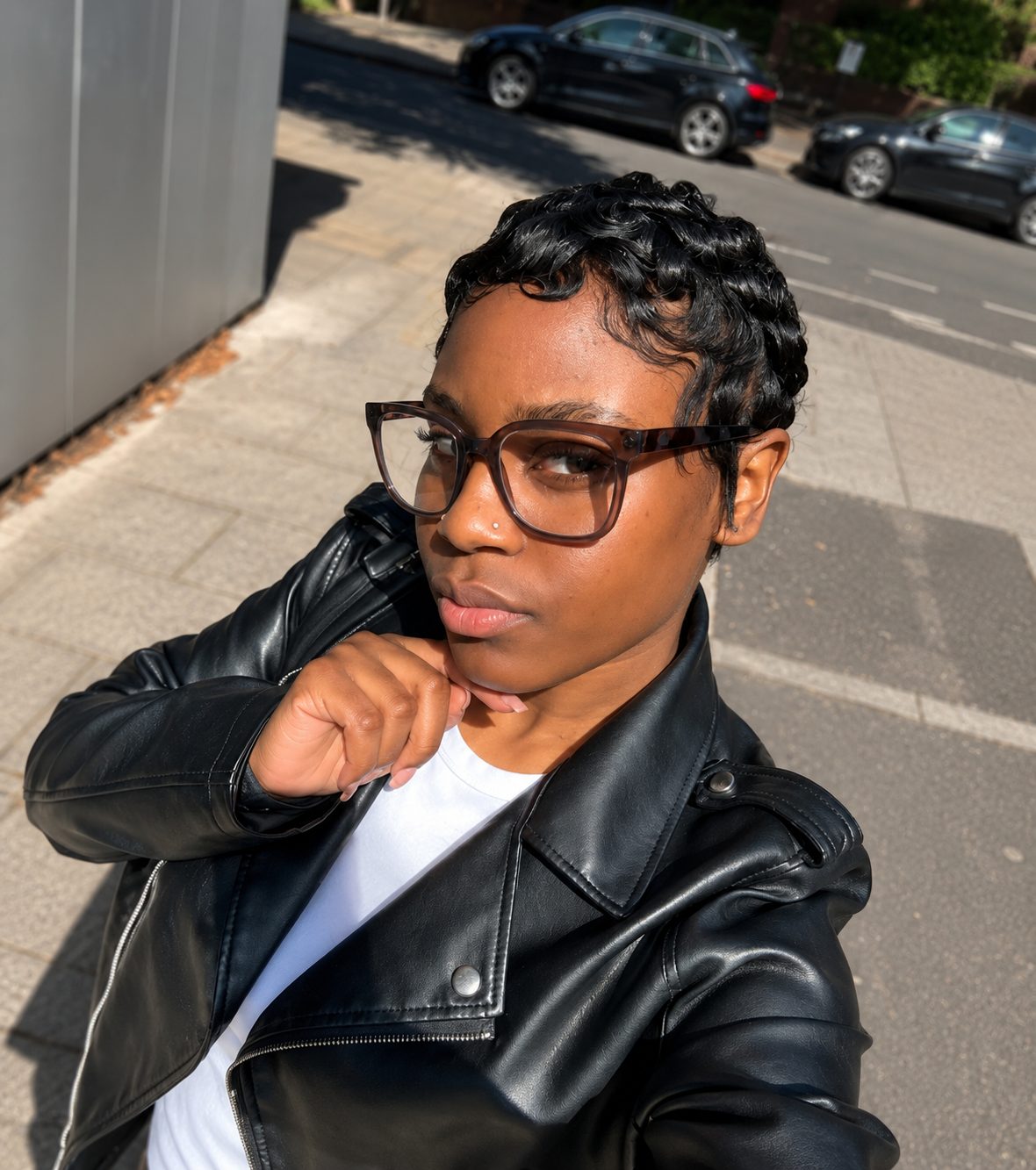 BBxLLuxeHair client in a black leather jacket and glasses, wearing a polished finger-wave pixie cut on a sunlit South East London street
